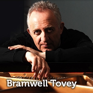 Photo of Bramwell Tovey, chin resting on his hands, resting on a piano